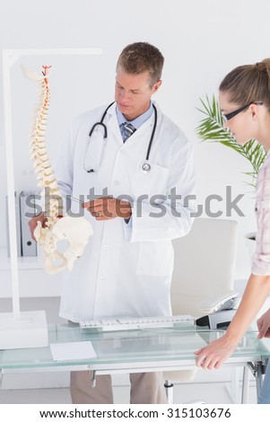 Doctor explaining anatomical spine to his patient in medical office
