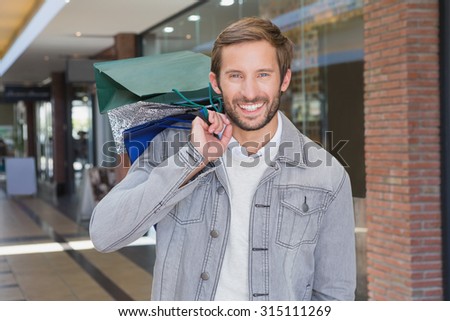 Young happy smiling man holding shopping bags in front of a store