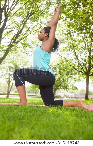 Young woman doing yoga on mat in the park