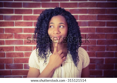 Model with finger on chin on red brick background