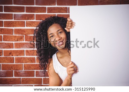 Smiling woman holding white board on red brick background
