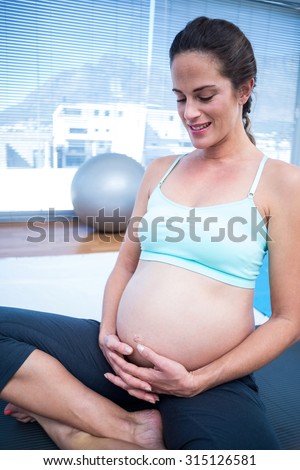 Pregnant woman looking her belly while resting in gym