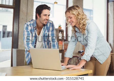 Colleagues smiling and working on laptop at office