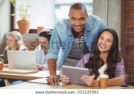 Portrait of smiling colleague with digital tablet in creative office