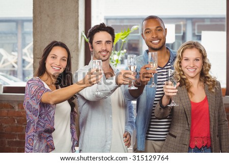 Portrait of colleagues toasting with champagne in creative office