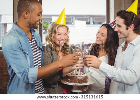 Colleagues laughing while toasting with champagne in bright creative office