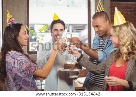 Colleagues toasting with champagne at birthday party in creative office