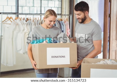 Man and woman volunteers with box standing in creative office