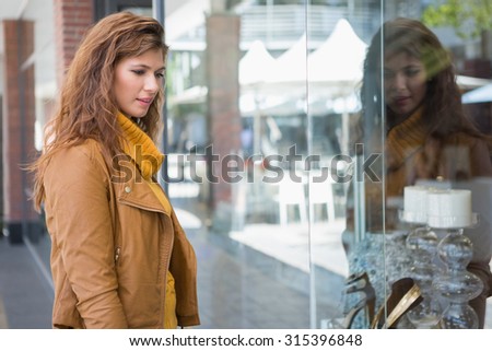 Smiling woman looking at products at the window at the shopping mall