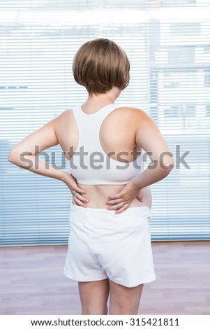 Rear view of pregnant woman exercising yoga at class