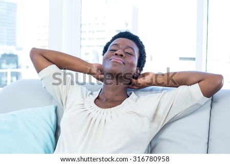 High angle view of woman relaxing with hands on neck on sofa at home