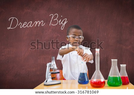 The word dream big and cute pupil playing scientist against desk