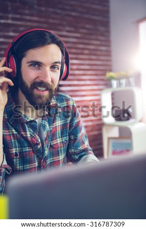 Portrait of businessman wearing headphones while working on laptop at office