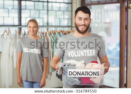 Portrait of volunteer holding clothes donation box in office