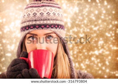 Happy blonde in winter clothes holding mug against white snow and stars design