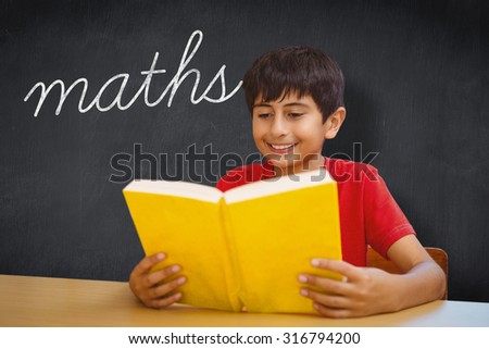 The word maths and cute boy reading book in library against blackboard