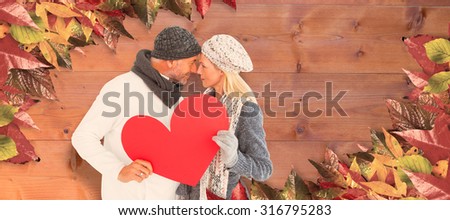 Couple holding heart while looking at each other against bleached wooden planks background