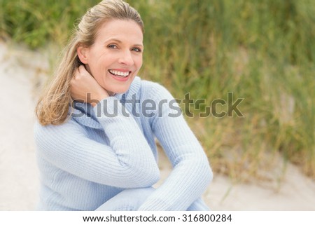 Smiling woman sitting on the sand at the beach