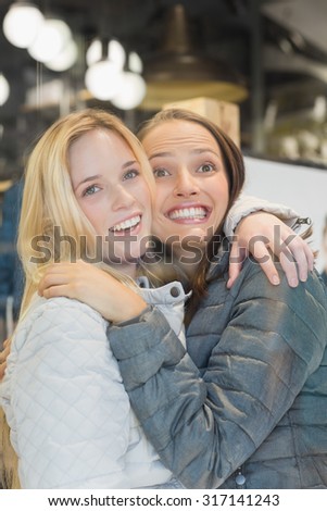 Two female friends embracing in clothes store