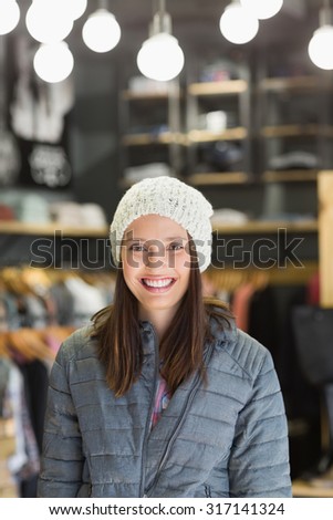 Smiling brunette with winter clothes looking at camera in clothes store