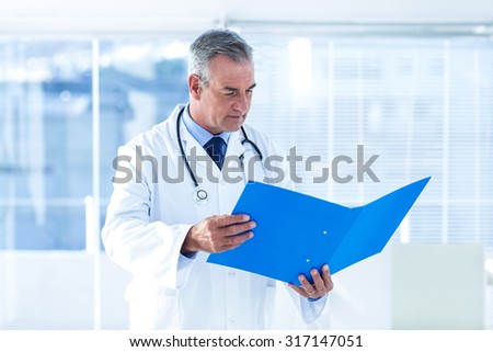 Male doctor reading and examining document in hospital