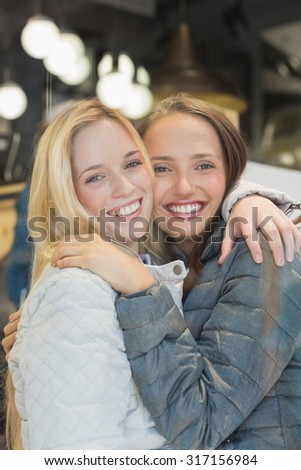 Two female friends with winter clothes smiling at camera in clothes store