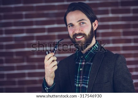 Portrait smiling handsome man smoking pipe in brick wall
