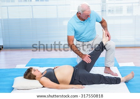 Physiotherapist messaging to pregnant woman lying on mattress at home