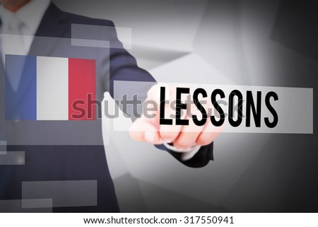 The word lessons and smiling businessman in suit pointing against abstract grey room