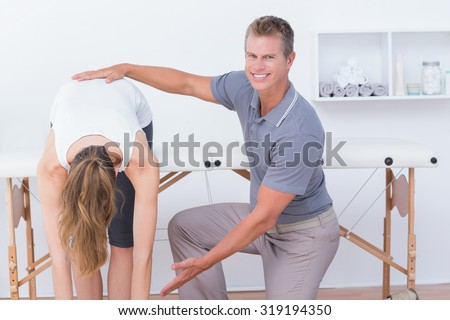 Happy doctor stretching a woman back in medical office