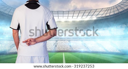 Rear view of rugby player with fingers crossed against rugby stadium