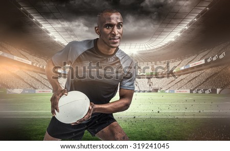 Rugby player in position to throw ball against rugby stadium
