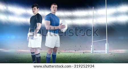 Rugby player holding rugby ball against rugby stadium