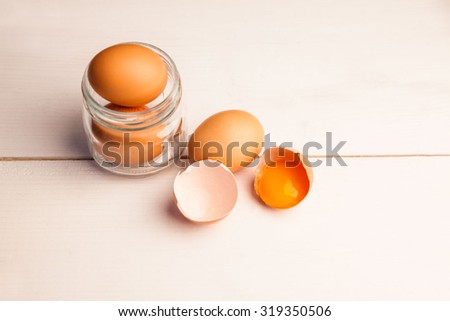 Overhead view of eggs in jar by broken egg shells on the table