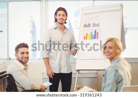 Portrait of smiling business people with whiteboard during meeting in creative office