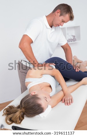 Doctor stretching a young woman back in medical office