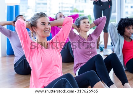 Attractive women doing sit ups on hardwood floor at fitness studio