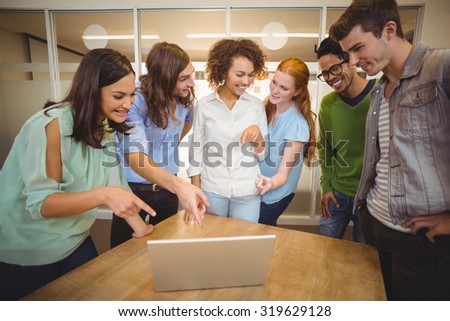 Smiling business people pointing at laptop in office