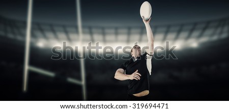 Rugby player catching a rugby ball against rugby stadium