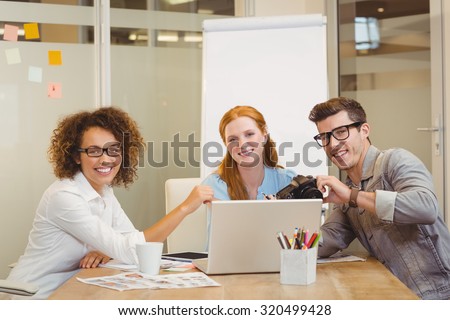 Portrait of smiling business people with camera and laptop in meeting at office