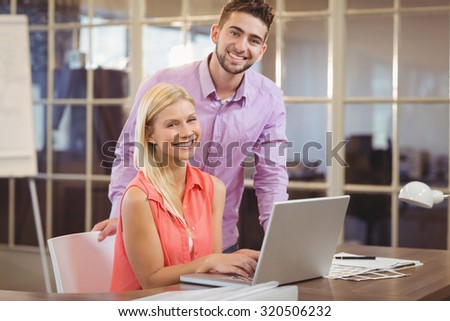 Portrait of happy business people with laptop in creative office