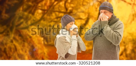 Sick mature couple blowing their noses against peaceful autumn scene in forest
