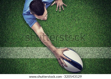 Rear view of rugby player lying in front with ball against pitch with line