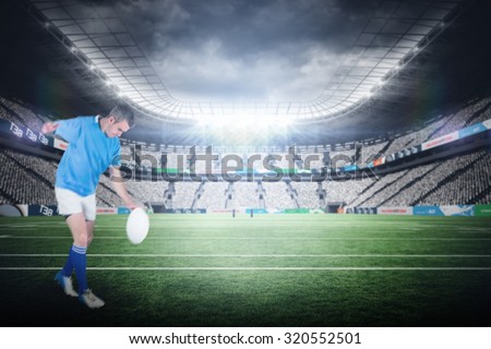 Rugby player kicking a rugby ball against rugby stadium