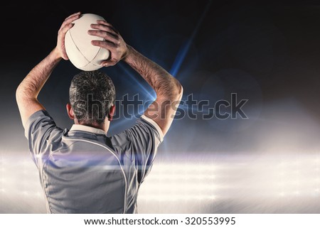 Rugby player about to throw a rugby ball against spotlights