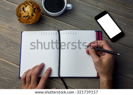 Cropped image of person writing on a diary at the desk