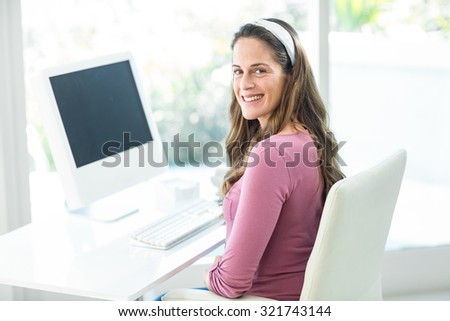 Portrait of happy pregnant businesswoman sitting on chair at desk in home office