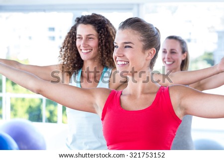 Cheerful women with arms outstretched in fitness studio