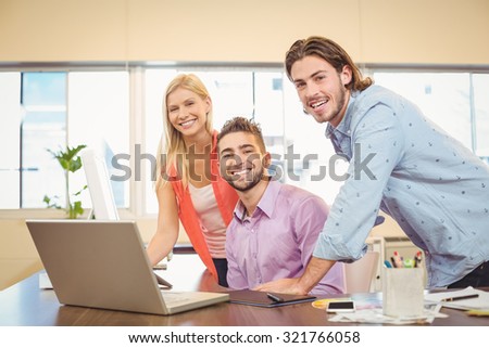 Portrait of happy business people with laptop working in creative office
