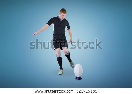 Rugby player doing a drop kick against blue background